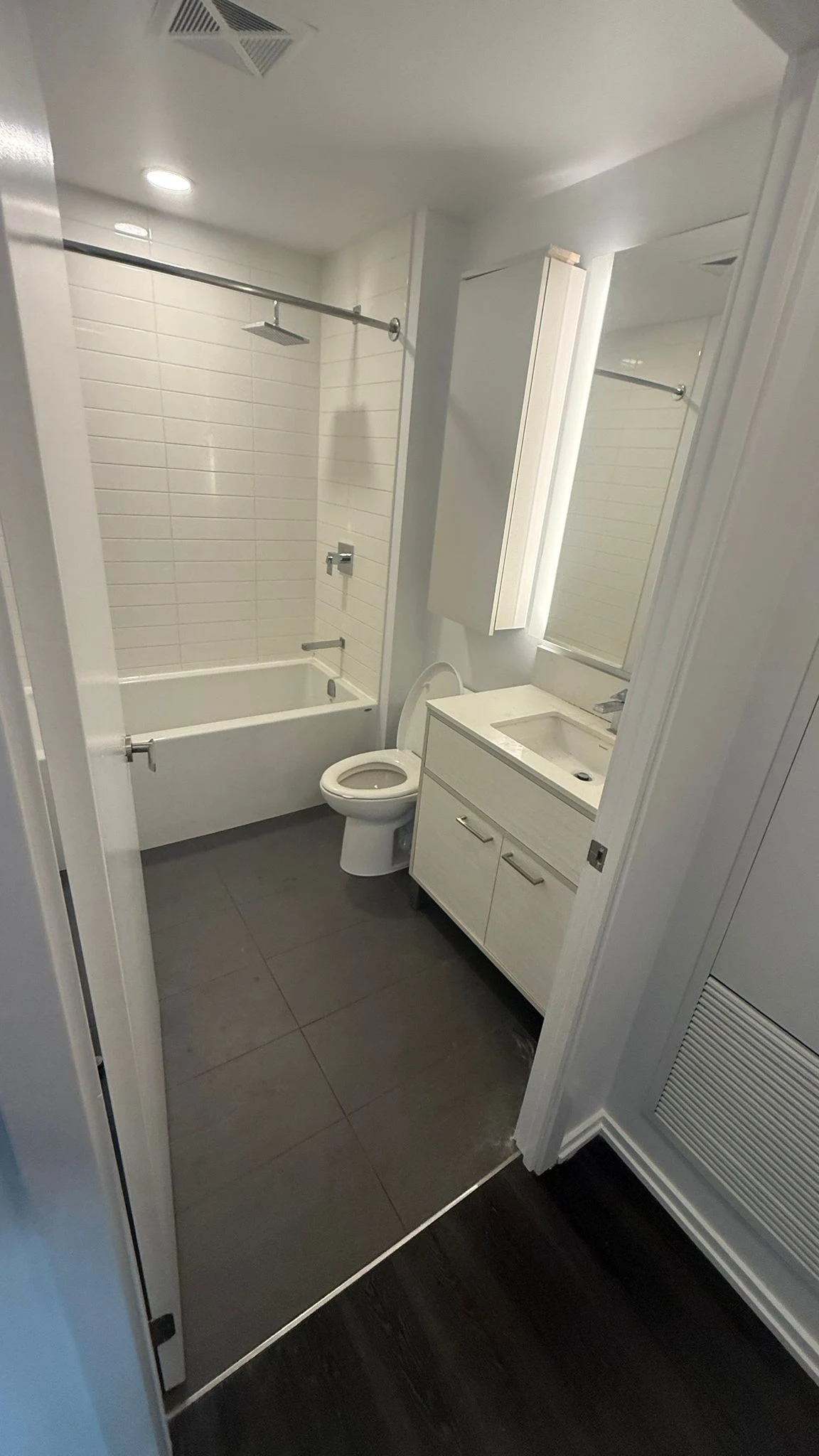 Finished MIRG bathroom renovation with a tiled tub surround, rainfall shower head and white vanity
